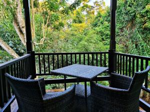 a table and chairs on a porch with a view of the forest at BeingSattvaa Luxury Ubud - CHSE Certified in Ubud