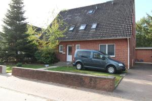 ein Van vor einem Backsteinhaus geparkt in der Unterkunft Ferienwohnung Düneneck 14 Gartenhaus in Sankt Peter-Ording