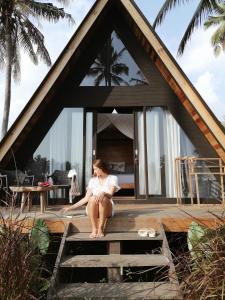 een vrouw die op de trappen van een huis zit bij Desa Cabins in Balian