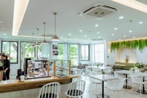 restauracja z białymi stołami, krzesłami i oknami w obiekcie RUS Hotel&Convention Ayutthaya w mieście Phra Nakhon Si Ayutthaya