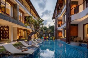a pool in the courtyard of a hotel with lounge chairs at Mokko Suites Batubelig in Canggu