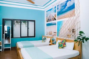 2 camas en una habitación con paredes azules en Blossom Sea Homestay Quy Nhơn en Quy Nhon
