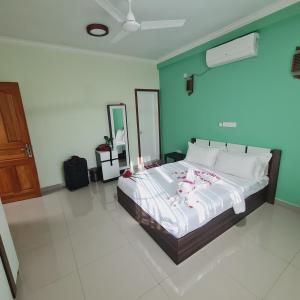 een slaapkamer met een bed met een blauwe muur bij Aanirustayinn in Hoarafushi