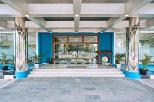 a lobby of a building with blue walls and columns at Horison TC UPI Serang in Banjar