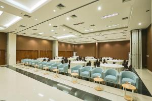 a conference room with tables and blue chairs at Horison TC UPI Serang in Banjar
