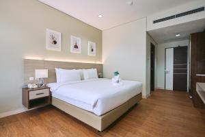 a bedroom with a large white bed and a bathroom at Horison TC UPI Serang in Banjar