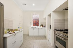 uma cozinha branca com armários brancos e uma janela em Waterfront Bliss Family Retreat em Geelong