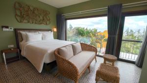 a bedroom with a bed and a couch and a window at CHiEM HoiAn - The Beachside Boutique Hotel & Villa in Hoi An +37 photos