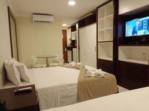 ein Hotelzimmer mit einem Bett und einem Flachbild-TV in der Unterkunft PONTA NEGRA FLAT APART in Natal