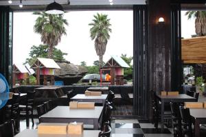 un restaurant avec des tables, des chaises et des palmiers dans l'établissement Ghost House, à Jeju