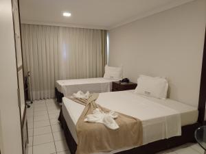 two beds in a hotel room with towels on them at PONTA NEGRA FLAT APART in Natal