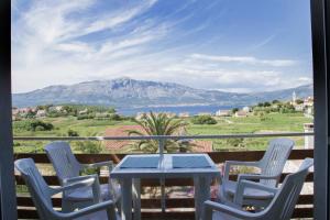 a table and chairs on a balcony with a view of a mountain at House Baglija in Lumbarda