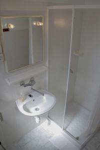 a white bathroom with a sink and a shower at House Baglija in Lumbarda
