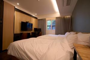 a bedroom with a large white bed and a window at D Well Hotel in Busan