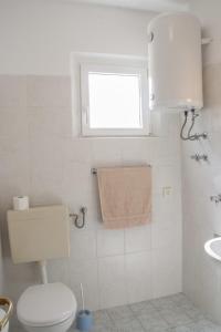 a bathroom with a toilet and a window and a sink at House Baglija in Lumbarda