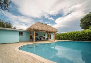 uma villa com uma piscina e um telhado de palha em Deerfield Beach Boca Raton with pool 1 mile from the beach em Deerfield Beach