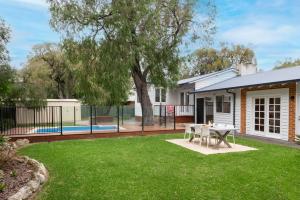 a backyard with a table and a fence at Summer Cottage in Dunsborough