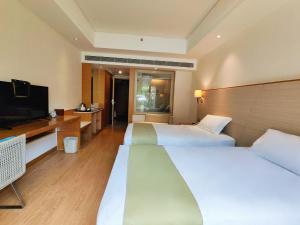 a hotel room with two beds and a flat screen tv at Ocean View Resort Yalong Bay in Sanya