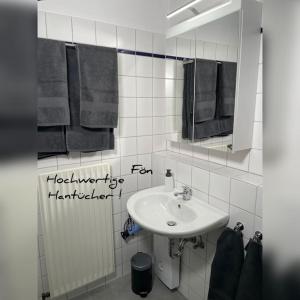 ein Badezimmer mit einem Waschbecken, einem Spiegel und Handtüchern in der Unterkunft Modernes Apartment in Oldenburg in Oldenburg
