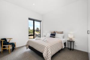 a white bedroom with a bed and a window at 3brm townhouse close to Geelong CBD in Geelong West