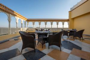 a restaurant with tables and chairs and a balcony at Sterling Balicha Udaipur in Udaipur