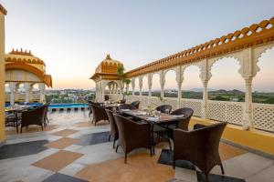 a restaurant with tables and chairs on a balcony at Sterling Balicha Udaipur in Udaipur