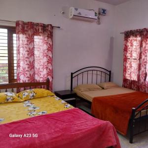 two beds in a room with red and yellow sheets at 1 Bedroom & Living Room for Friends & Families in Chāmundi