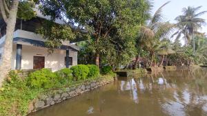 a house with a river in front of a building at VALENTINE'S RICE BOWL HOME STAY in Alleppey