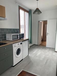 una cocina con lavadora y microondas en Appartement 35 m2 1er étage 200 m de la mer avec jardin, en Luc-sur-Mer 5 fotos más