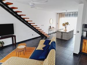 Una sala de estar con un sofá azul y una escalera. en La Villa Manaïck, en Saint-André