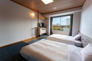 una camera d'albergo con due letti e una finestra di KAMENOI HOTEL Kusatsu Yubatake a Kusatsu