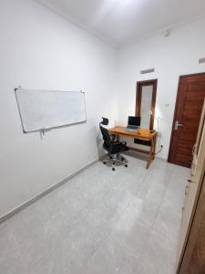 een kantoor met een bureau, een stoel en een witte muur bij Tropical home with office in Krambitan