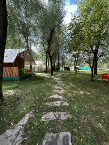a path in a field with trees and a building at The Posh Camps in Pahalgām