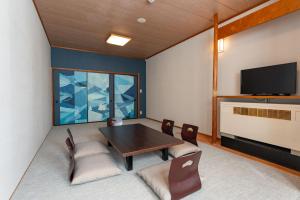a dining room with a table and chairs and a tv at KAMENOI HOTEL Kusatsu Yubatake in Kusatsu