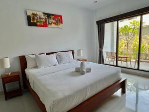 1 dormitorio con 1 cama blanca grande y balcón en CG Guesthouse Canggu en Canggu