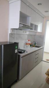 kuchnia z czarną lodówką i białymi szafkami w obiekcie Apartemen Skylounge Makassar w mieście Manda