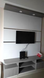 TV de pantalla plana en una pared blanca en Apartemen Skylounge Makassar, en Mandai