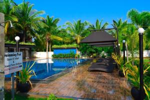 una piscina con palmeras y un cartel junto a ella en Hotel Green Garden, en Trincomalee