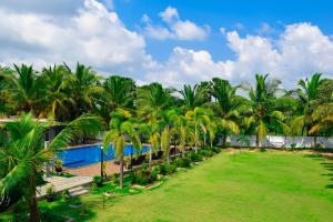 a resort with a pool and palm trees at Hotel Green Garden in Trincomalee