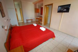 a bedroom with a red bed with towels on it at Sunrise Hotel in Agia Ermioni