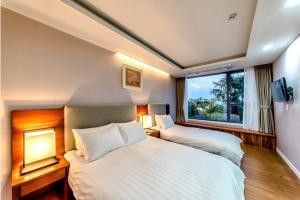 a bedroom with two beds and a window at The Shimpang Spa & Poolvilla in Seogwipo