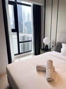 a bed with a towel on it in front of a window at Axon Residence at Pavilion KLCC KL Tower view by KIMIRO in Kuala Lumpur
