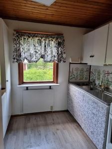 cocina con ventana, fregadero y encimera en Rustikales Hexenhäuschen, en Stöde