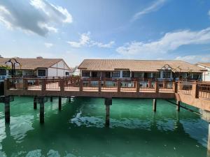 a wooden bridge over water with houses on it at Alpine LXPD Water Chalet in Port Dickson
