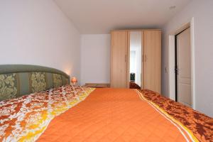 a bedroom with a large bed with an orange bedspread at Ferienwohnung-6-15 in Baabe