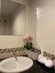 a bathroom sink with a mirror and a vase of pink flowers at Elephant Room in Patong Beach