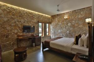 Hālol的住宿－Vikrama Sarovar Portico Pavagadh，一间卧室配有一张床、一张书桌和一台电视。