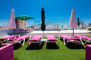 een groep roze stoelen en parasols op een dak bij Hotel Sireno Torremolinos - Adults Only, Ritual Friendly in Torremolinos