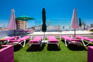 a group of pink chairs and umbrellas on a roof at Hotel Sireno Torremolinos - Adults Only, Ritual Friendly in Torremolinos