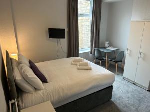 1 dormitorio con cama con almohadas y escritorio en The Clifton Seafront Hotel, en Morecambe